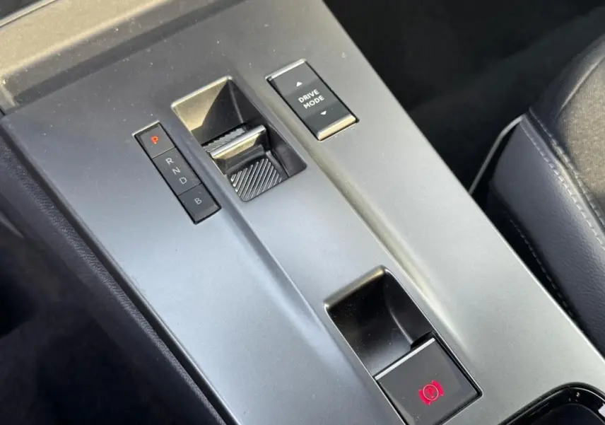 Gros plan sur la console centrale grise de l’Opel Mokka électrique 2025, montrant la commande de boîte auto et le bouton Drive Mode.