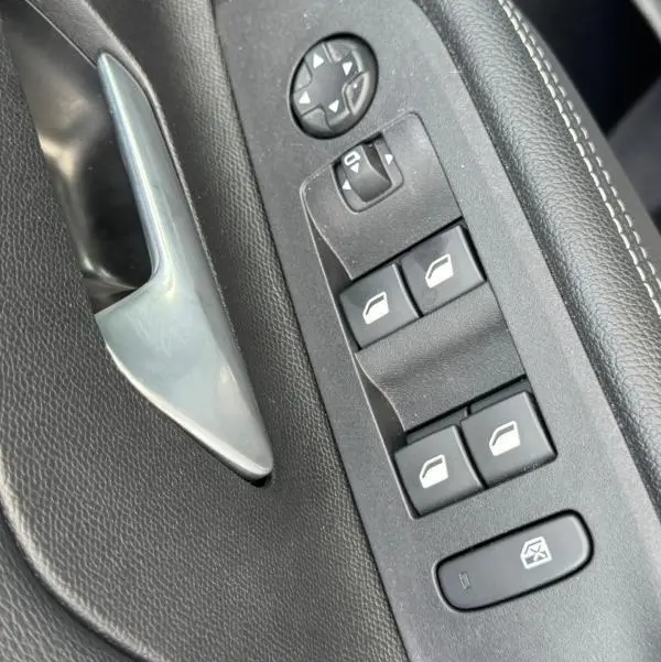 Gros plan sur la commande des vitres et rétroviseurs côté gauche de la porte intérieure grise de l’Opel Mokka électrique 2025.