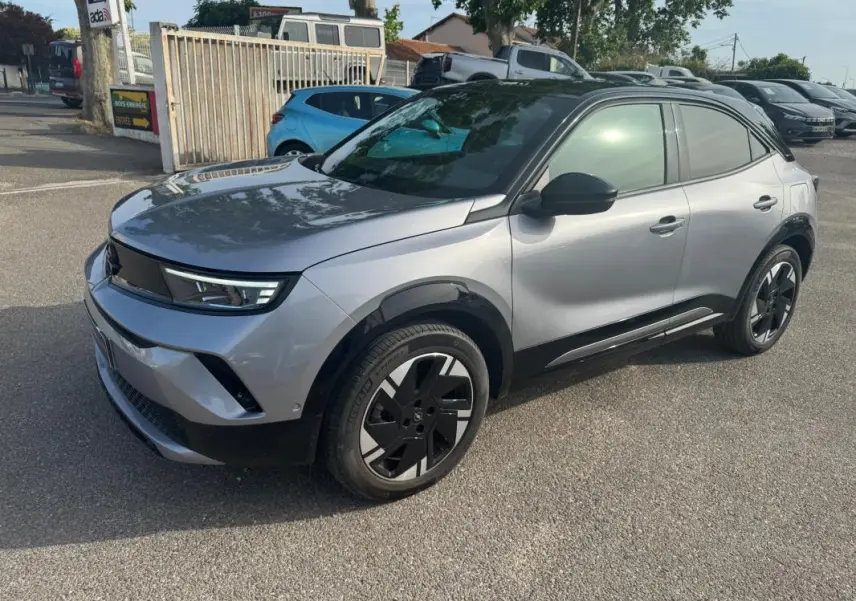 Opel Mokka électrique gris en 3/4 avant droit, avec jantes alliage noires et vitres surteintées.