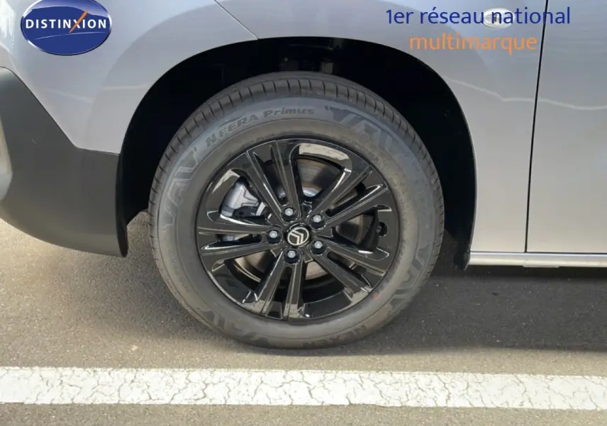 Gros plan sur la roue avant droite noire brillante du Citroën Berlingo gris Artense métal, avec logo central visible.
