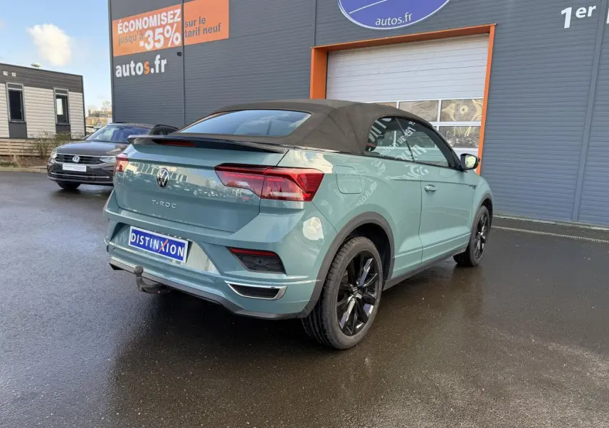 Vue 3/4 arrière d'un Volkswagen T-Roc Cabriolet vert cactus avec capote noire et attelage amovible.
