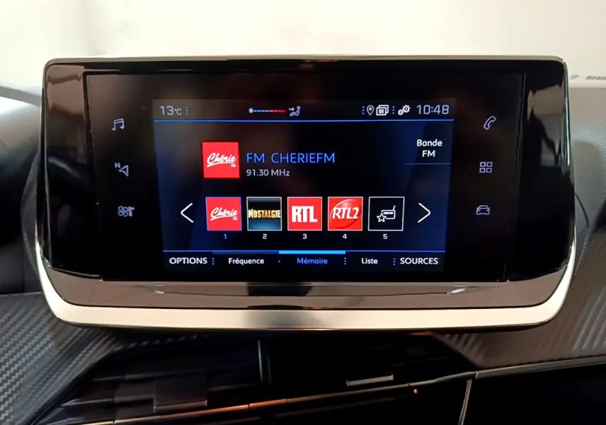 Écran tactile central du tableau de bord du Peugeot 2008 gris clair, affichant les stations radio FM