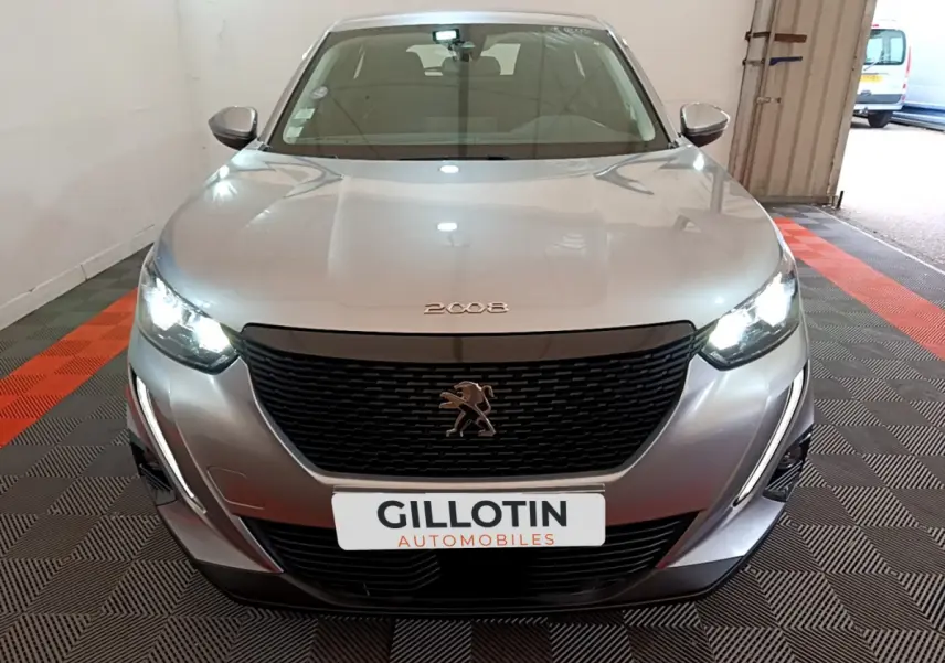 Peugeot 2008 gris clair vue de face avec phares LED allumés et calandre noire distinctive.