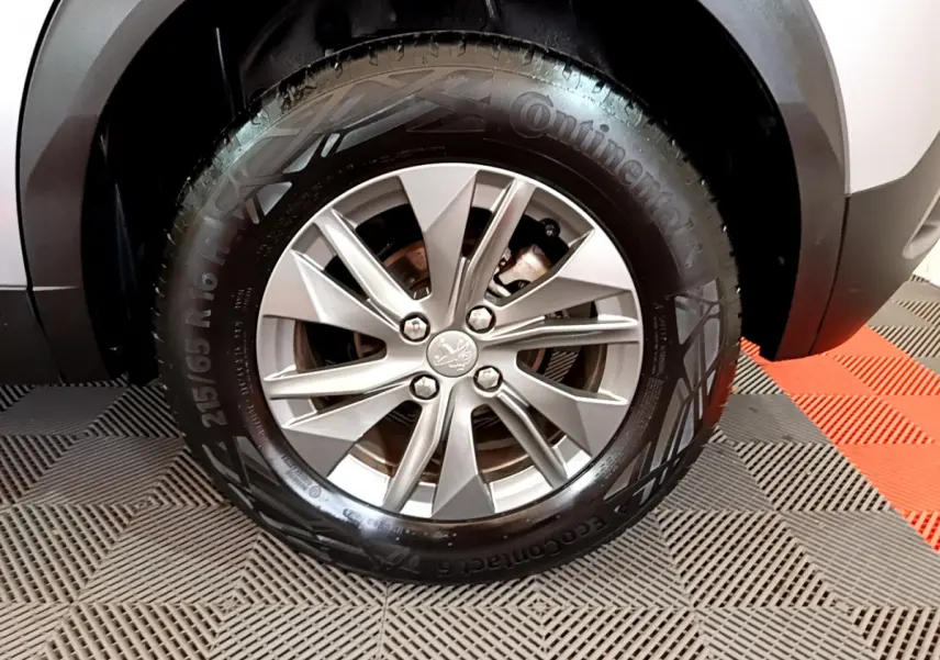 Gros plan sur la roue avant droite du Peugeot 2008 gris clair, mettant en valeur la jante alliage et le pneu Continental.