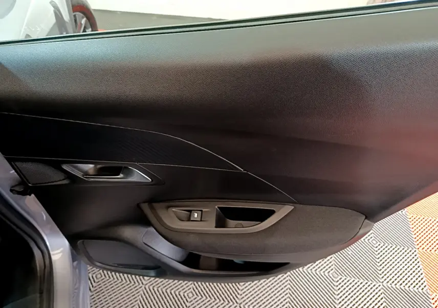 Vue rapprochée de la porte côté gauche gris clair du Peugeot 2008 avec poignée et commande de vitre intégrée.
