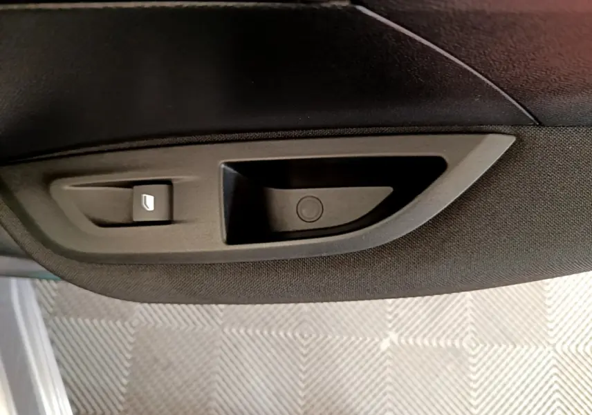 Poignée intérieure de porte côté gauche en plastique noir sur Peugeot 2008 gris clair, vue rapprochée.