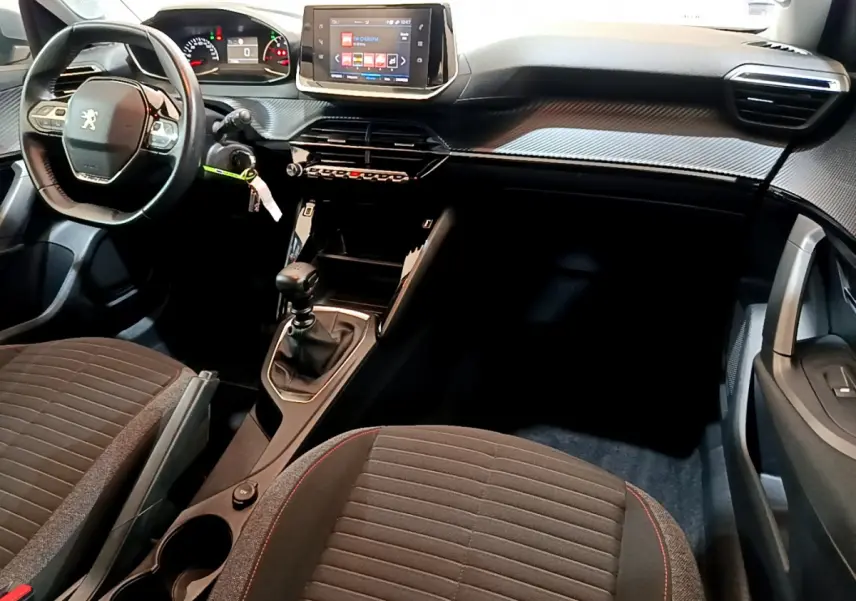 Intérieur avant du Peugeot 2008 2020 avec volant cuir, tableau de bord tactile et sièges tissu gris à surpiqûres rouges.