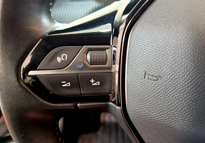 Gros plan sur les commandes gauche du volant cuir noir du Peugeot 2008 gris clair, version 2020 Active Business.