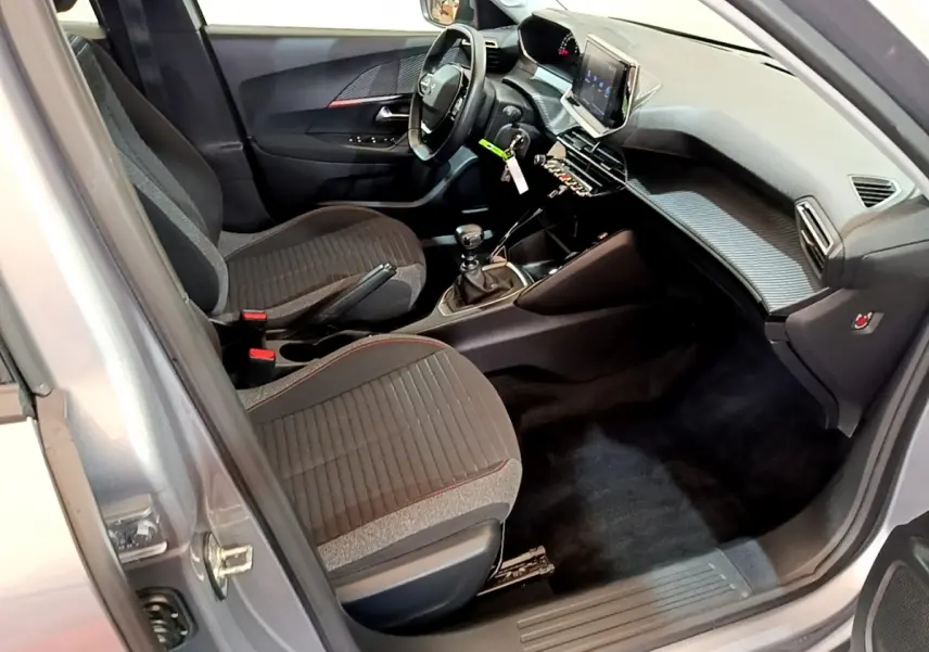 Intérieur avant droit du Peugeot 2008 gris clair 2020, avec tableau de bord moderne et sièges tissu noirs.