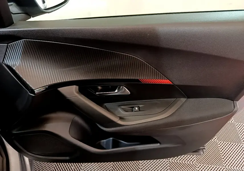 Détail de la porte côté conducteur avec insert imitation carbone et bande rouge sur Peugeot 2008 gris clair 2020.