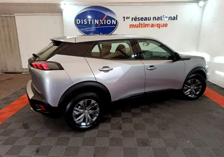 Peugeot 2008 gris clair vue de profil côté droit dans un showroom avec logo Distinxion en arrière-plan.