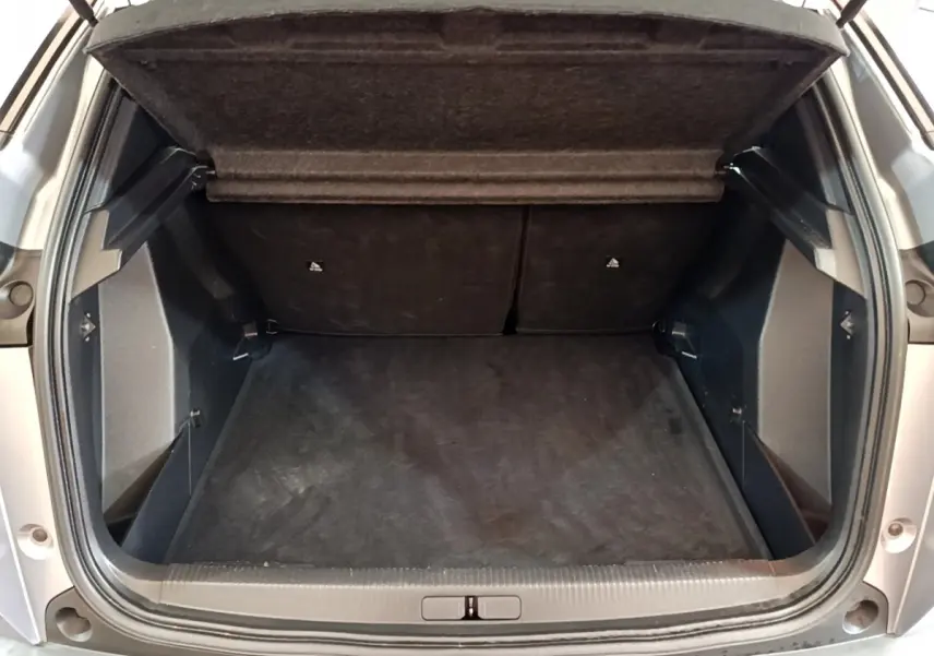 Coffre ouvert vu de l'arrière d'un Peugeot 2008 gris clair, montrant un espace de chargement propre et spacieux.