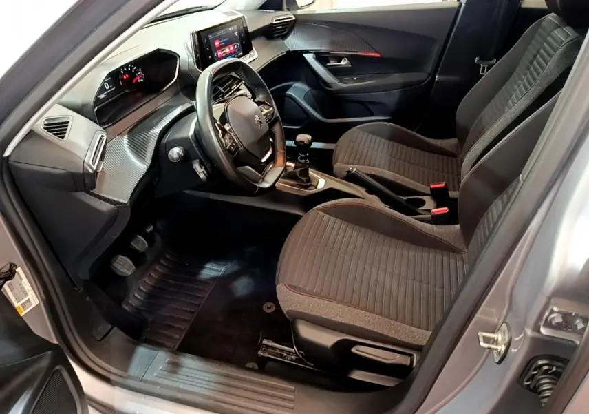 Intérieur avant droit d'une Peugeot 2008 gris clair 2020, volant cuir, écran tactile et sièges tissu gris.