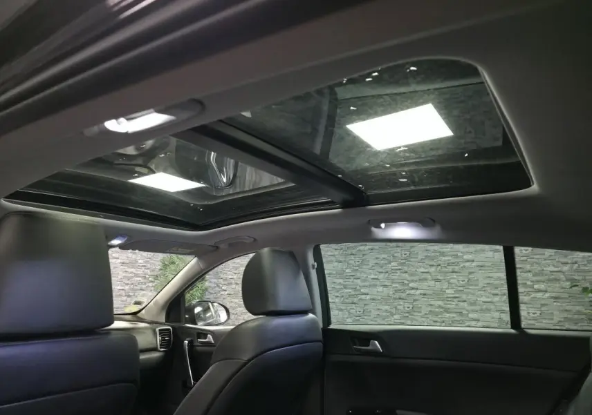 Intérieur noir du Kia Sportage 2021 vu côté droit, avec toit vitré panoramique et sièges cuir.