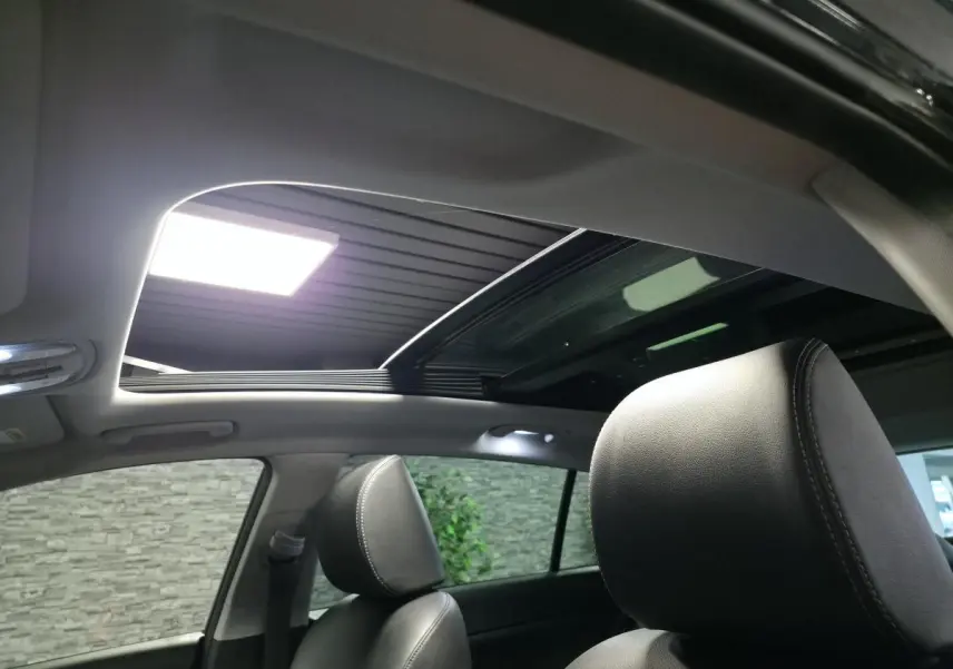 Vue intérieure du toit vitré panoramique ouvert du Kia Sportage noir avec sièges avant en cuir noir.