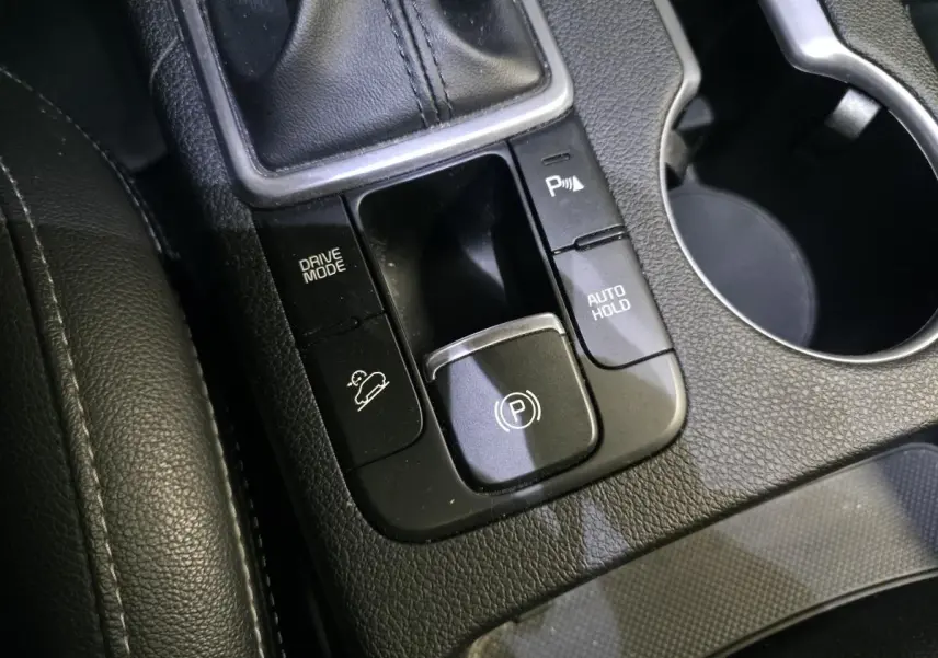Gros plan sur la console centrale noire du Kia Sportage 2021 avec commandes frein électrique et mode de conduite.