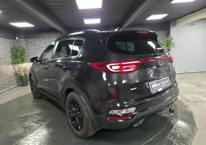 Vue 3/4 arrière gauche d'un KIA Sportage noir Black Edition avec feux arrière LED et jantes alliage noires.