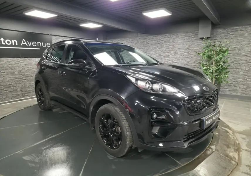 KIA Sportage noir 3/4 avant droit en intérieur avec jantes noires et calandre Black Edition.