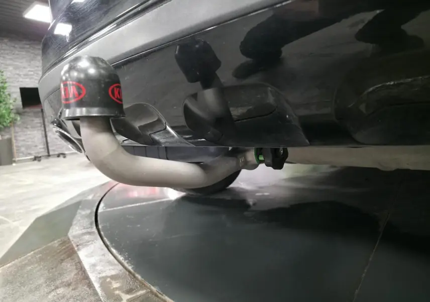Gros plan sur l'attelage de remorque gris sous le pare-chocs arrière noir métallisé du KIA Sportage Black Edition.