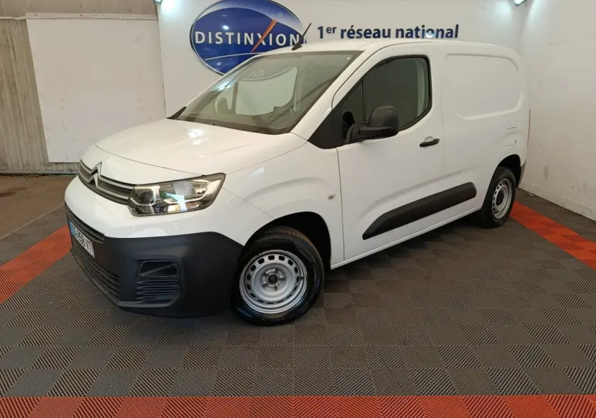 Vue 3/4 avant droit d'un Citroën Berlingo blanc 2022 avec pare-chocs noir et jantes acier en intérieur showroom.