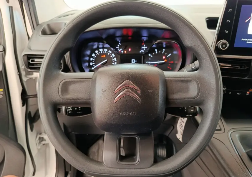 Vue centrée sur le volant noir du Citroën Berlingo blanc, avec tableau de bord et écran tactile visibles à droite.