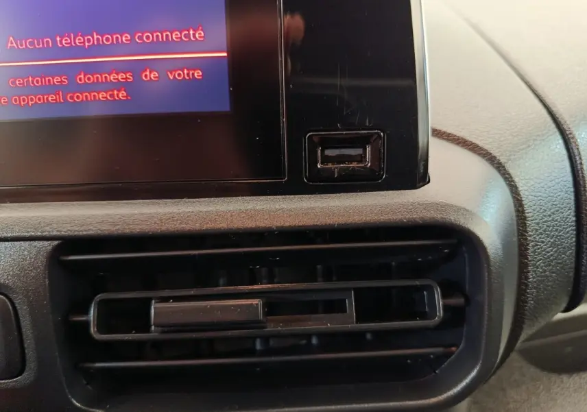 Détail intérieur du tableau de bord du Citroën Berlingo blanc 2022, avec prise USB et écran tactile.