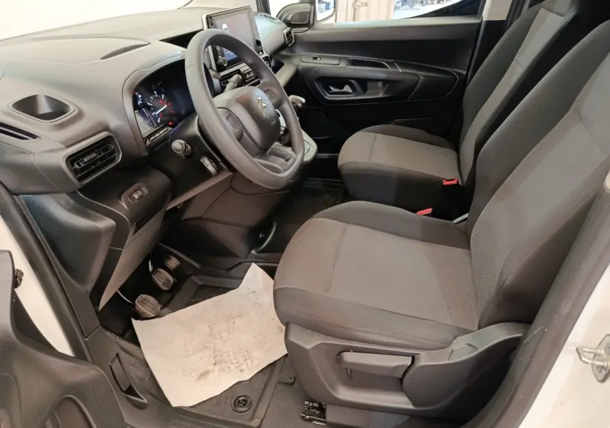 Vue intérieure côté conducteur du Citroën Berlingo blanc 2022, montrant le volant, les sièges et le tableau de bord.