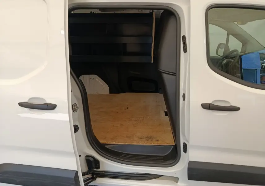 Vue latérale gauche d’un Citroën Berlingo blanc 2022 avec porte coulissante ouverte montrant l’espace de chargement en bois.