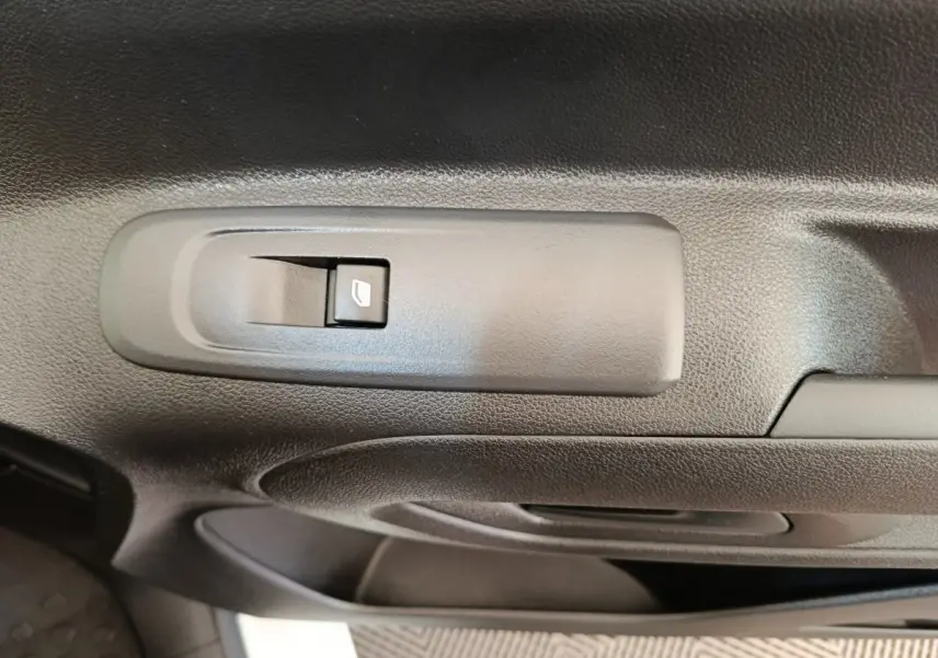 Gros plan sur le bouton de commande de la vitre électrique côté conducteur du Citroën Berlingo blanc, intérieur noir.