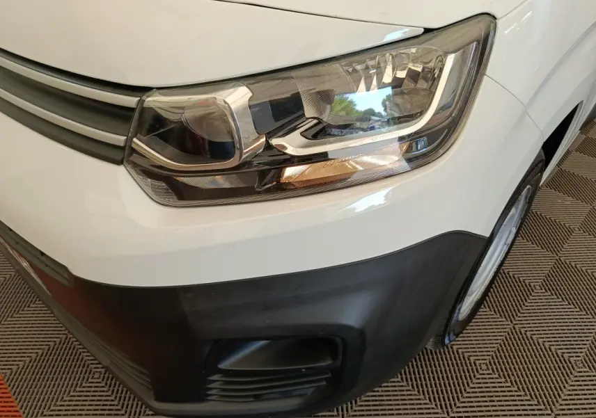 Gros plan sur le phare avant droit blanc du Citroën Berlingo 2022 avec pare-chocs noir et calandre grise.