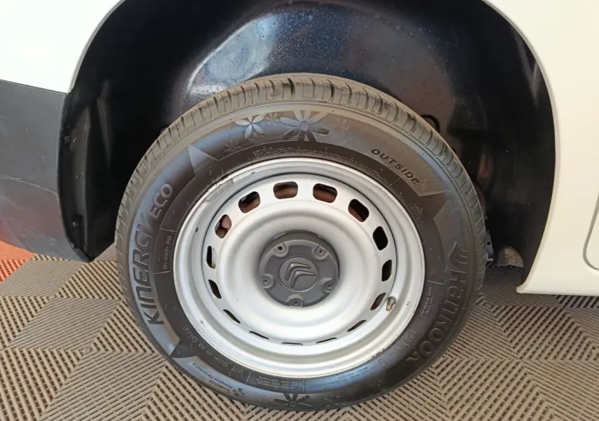 Gros plan sur la roue avant droite en jante acier grise du Citroën Berlingo blanc, avec logo Citroën au centre.