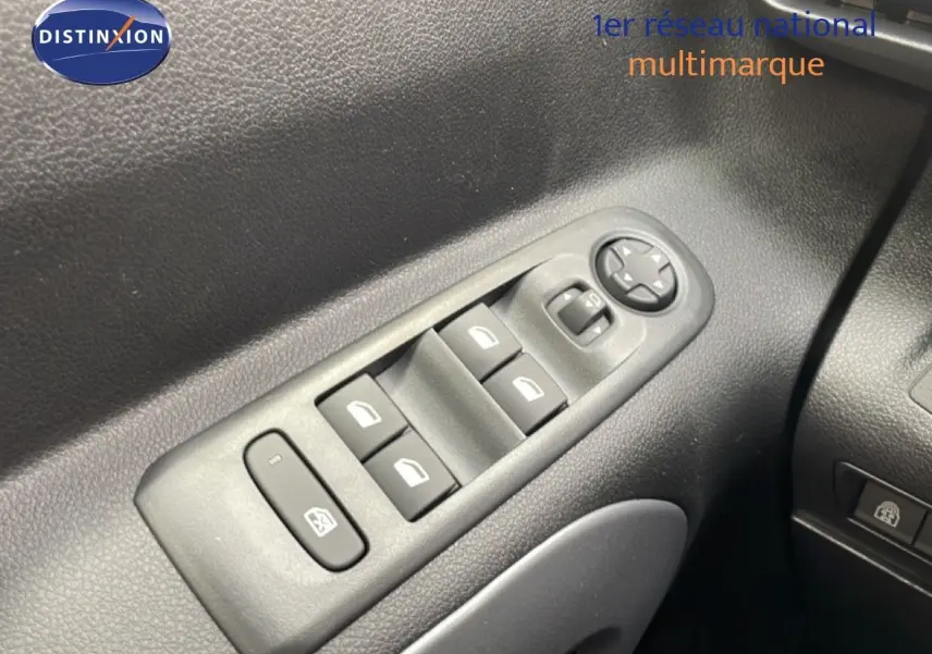 Gros plan sur les commandes des vitres électriques et rétroviseurs côté gauche du Citroën Berlingo gris 2026.
