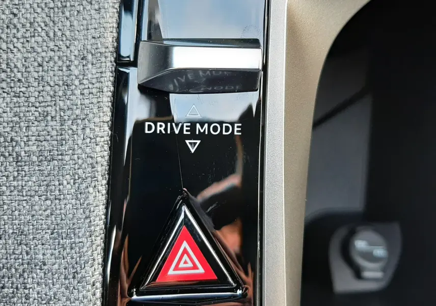 Gros plan sur la commande Drive Mode et le bouton de warning rouge dans l'habitacle du Peugeot 5008 bleu Ingaro 2025.