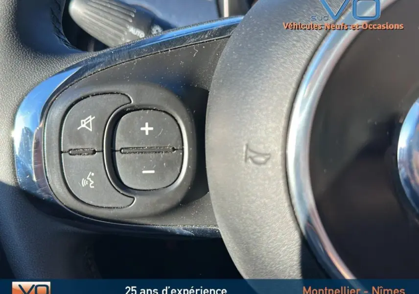 Gros plan sur les commandes vocales et volume au volant d'une FIAT 500C noire 2024, version hybride essence.