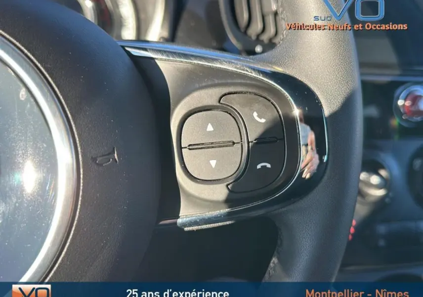 Gros plan sur les commandes du volant d'une FIAT 500C noire 2024, mettant en valeur les boutons de gestion d'appels téléphoniques.