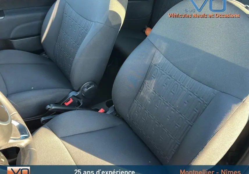 Gros plan sur les sièges avant noirs du Fiat 500C 2024, avec motif texturé et volant partiellement visible côté gauche.