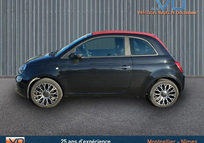 Profil côté gauche d'une FIAT 500C noire avec toit rouge, roues alliage et roue de secours visible, modèle 2024 hybride.