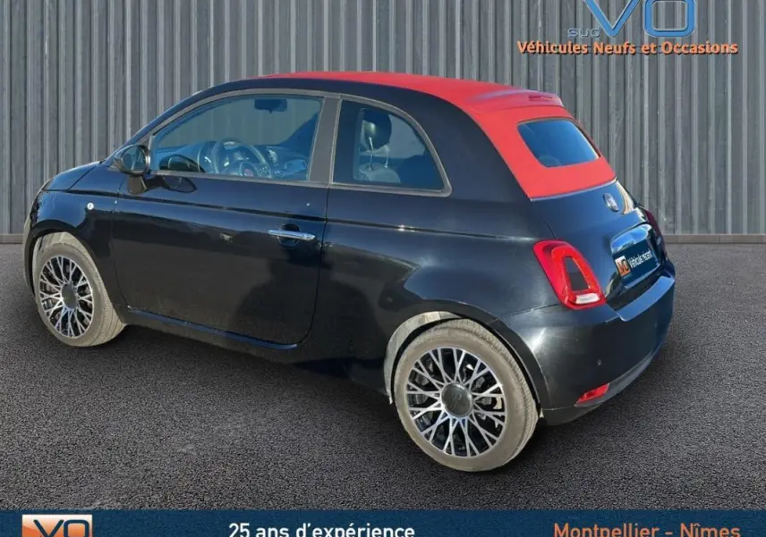 Vue 3/4 arrière droite d'une Fiat 500C noire avec toit rouge, jantes originales et roue de secours visible