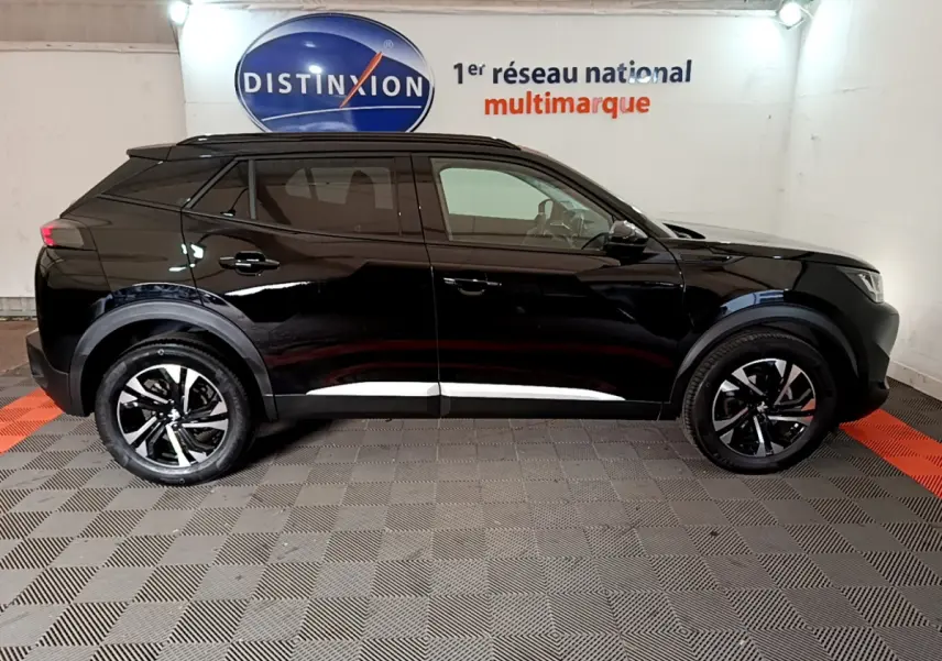 Profil côté gauche d'un Peugeot 2008 noir 2021 dans un showroom avec jantes bicolores et toit noir.