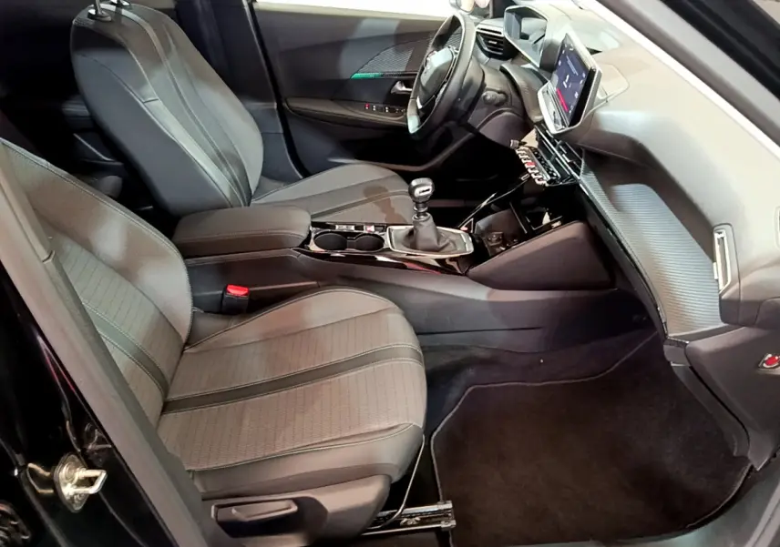 Intérieur avant droit du Peugeot 2008 noir 2021, sièges tissu, tableau de bord avec écran tactile et boîte manuelle.