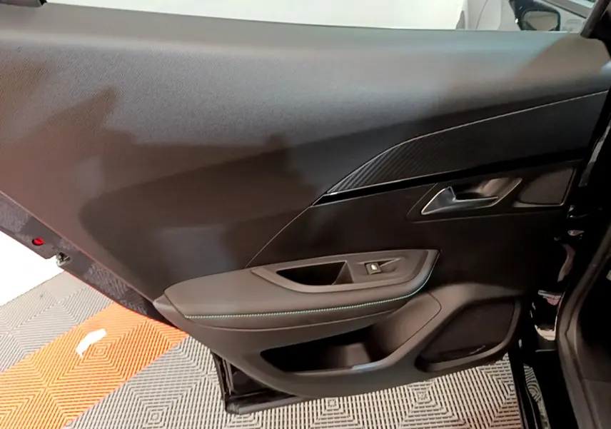 Vue rapprochée de la porte arrière droite noire du Peugeot 2008 avec garniture tissu et surpiqûres bleues.