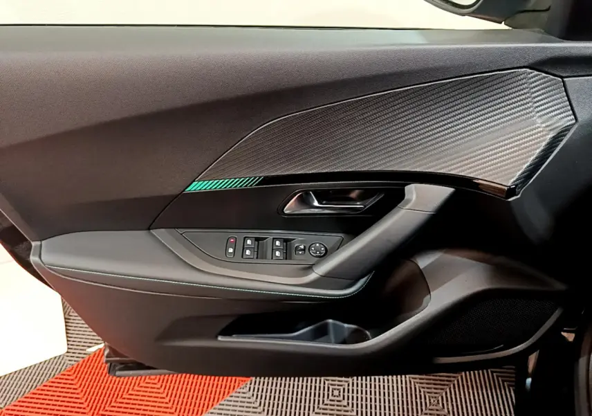 Vue rapprochée de la porte côté gauche noire du Peugeot 2008 avec insert effet carbone et commandes de vitres électriques.