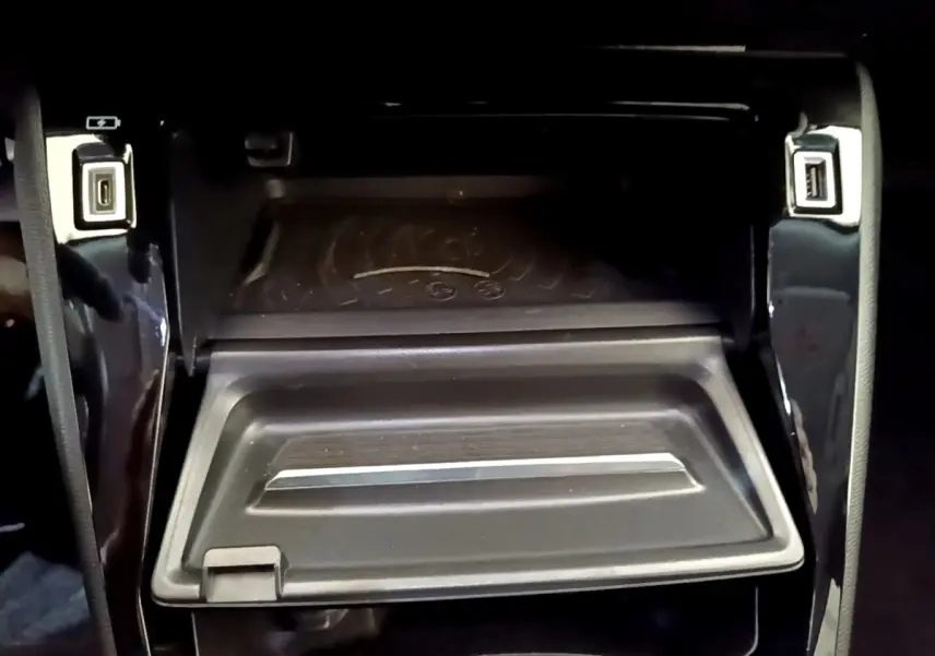 Gros plan sur la zone de recharge sans fil et ports USB avant du Peugeot 2008 noir, intérieur moderne et épuré.