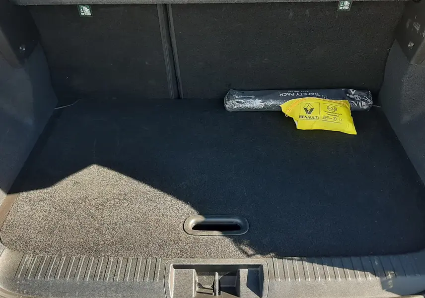 Coffre ouvert du Renault Captur gris Cassiopée, vue arrière montrant un espace de chargement propre avec kit de sécurité.