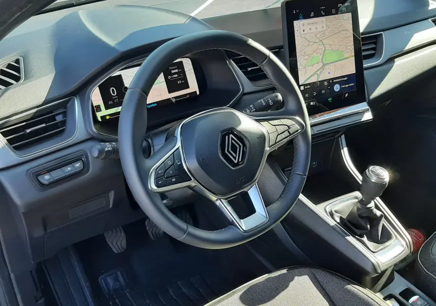 Vue intérieure du poste de conduite du Renault Captur II 1.0 TCE 90CH TECHNO 2025, avec volant multifonction, écran tactile vertical et boîte manuelle.