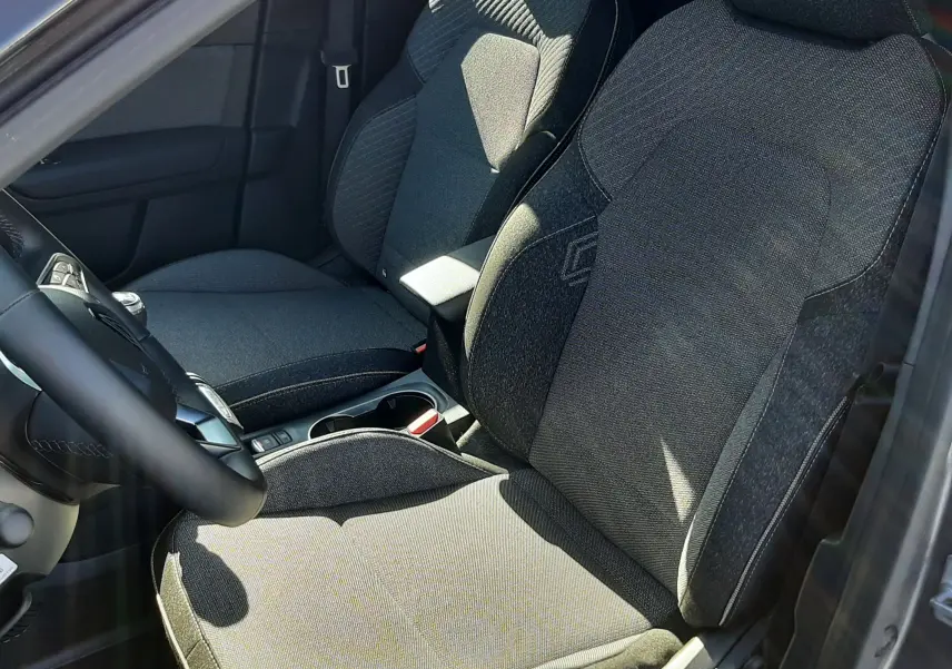 Vue intérieure côté conducteur du Renault Captur II gris Cassiopée, mettant en valeur les sièges en tissu gris et la console centrale.