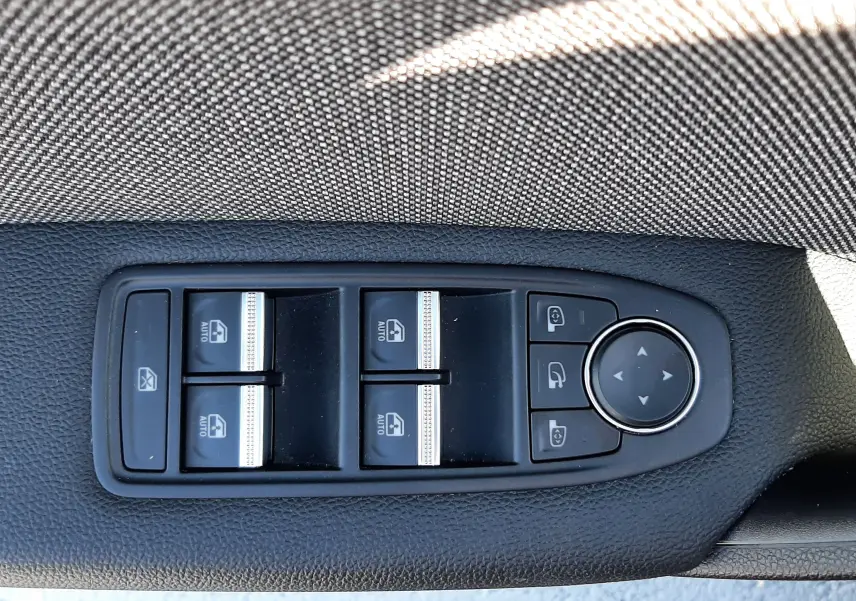 Gros plan sur les commandes de lève-vitres et rétroviseurs du côté gauche intérieur du Renault Captur II gris Cassiopée.