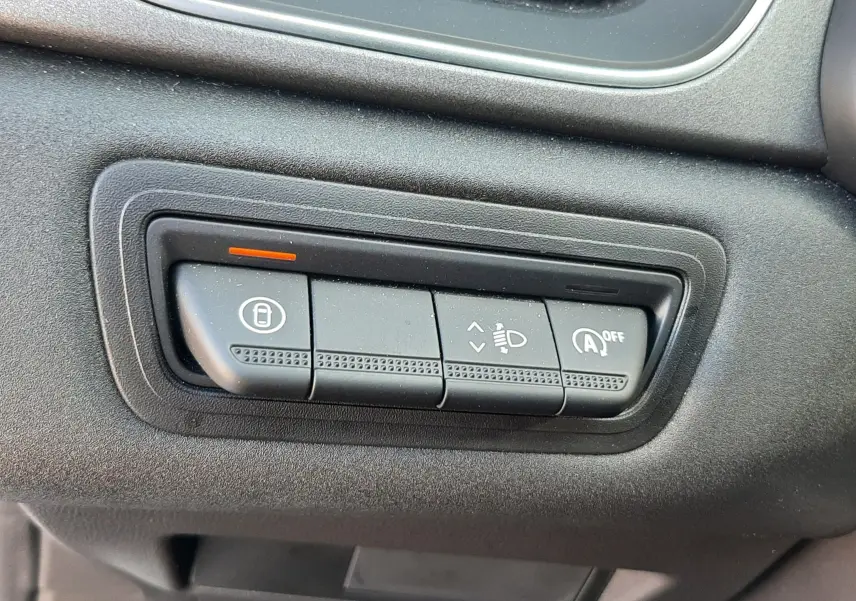 Gros plan sur les commandes de réglage des phares et du système start-stop, tableau de bord noir du Renault Captur gris Cassiopée.