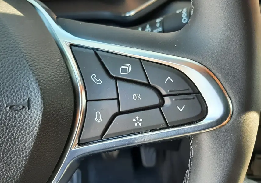 Gros plan sur les commandes multifonctions à droite du volant du Renault Captur II gris Cassiopée, avec affichage numérique en arrière-plan.