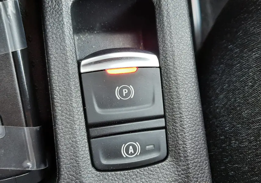 Gros plan sur les boutons de frein à main électronique et arrêt auto du Renault Captur gris Cassiopée, intérieur tissu noir.
